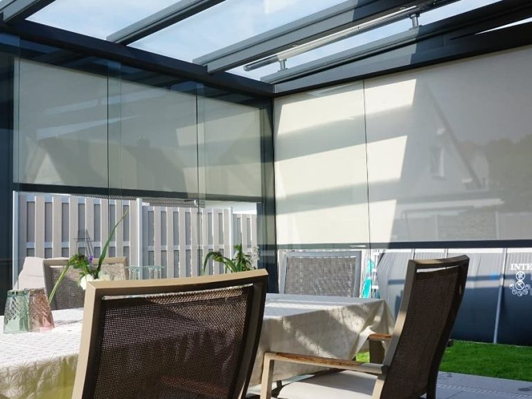 Kaltwintergarten mit linksrum Schiebeelementen und LEWENS Senkrechtmarkisen und LEWENS Aufglasmarkise als Sonnenschutz